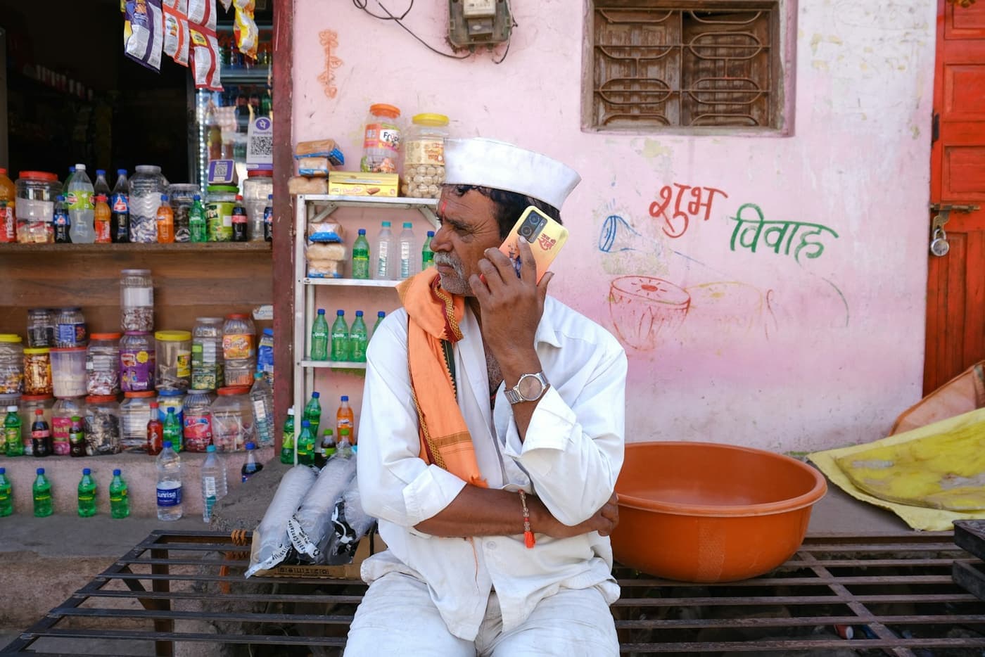 A shopkeeper in his shop taking an order on his phone